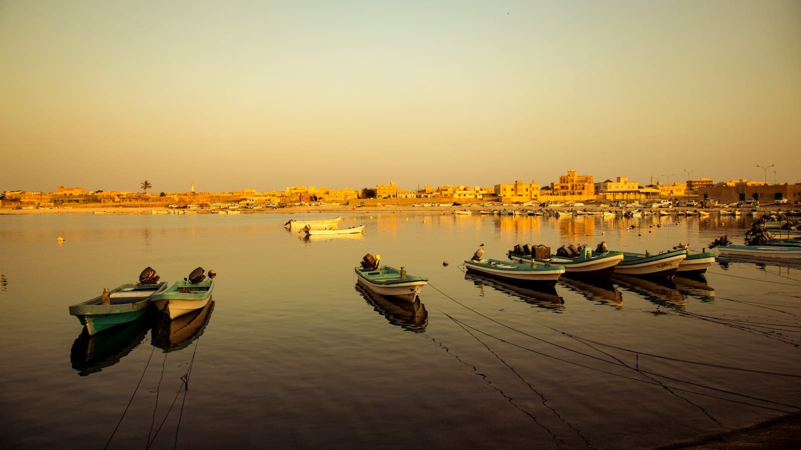 Small fishing boats moored in a calm bay on Oman's coast at golden hour