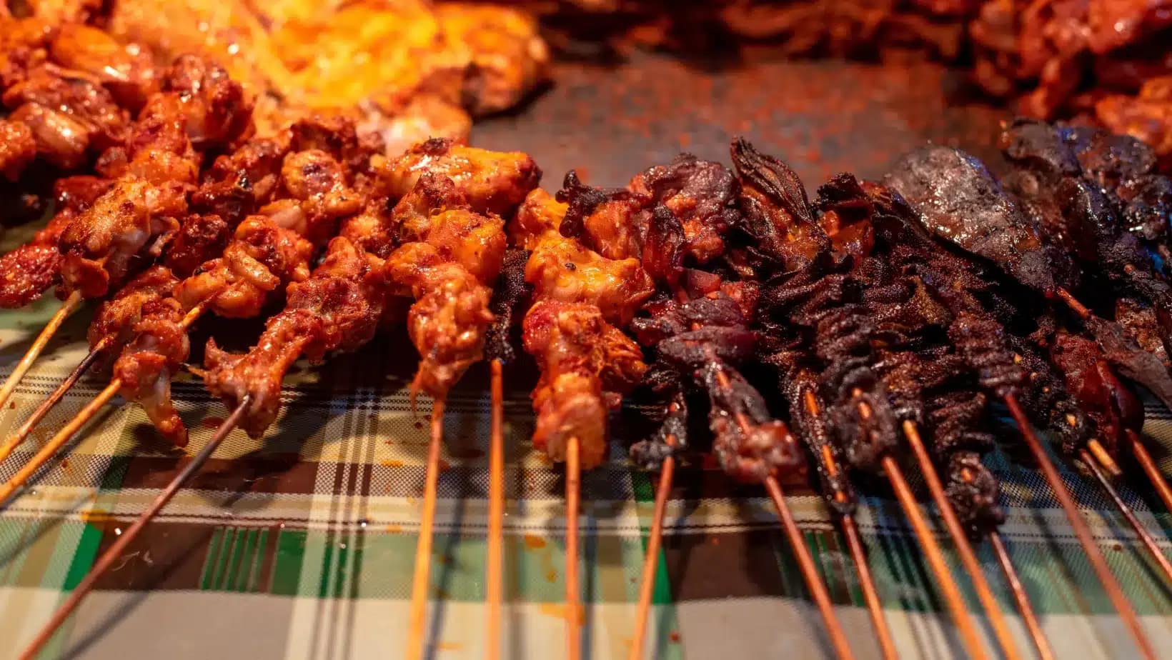 Skewers of suya grilling at a Nigerian street food stall