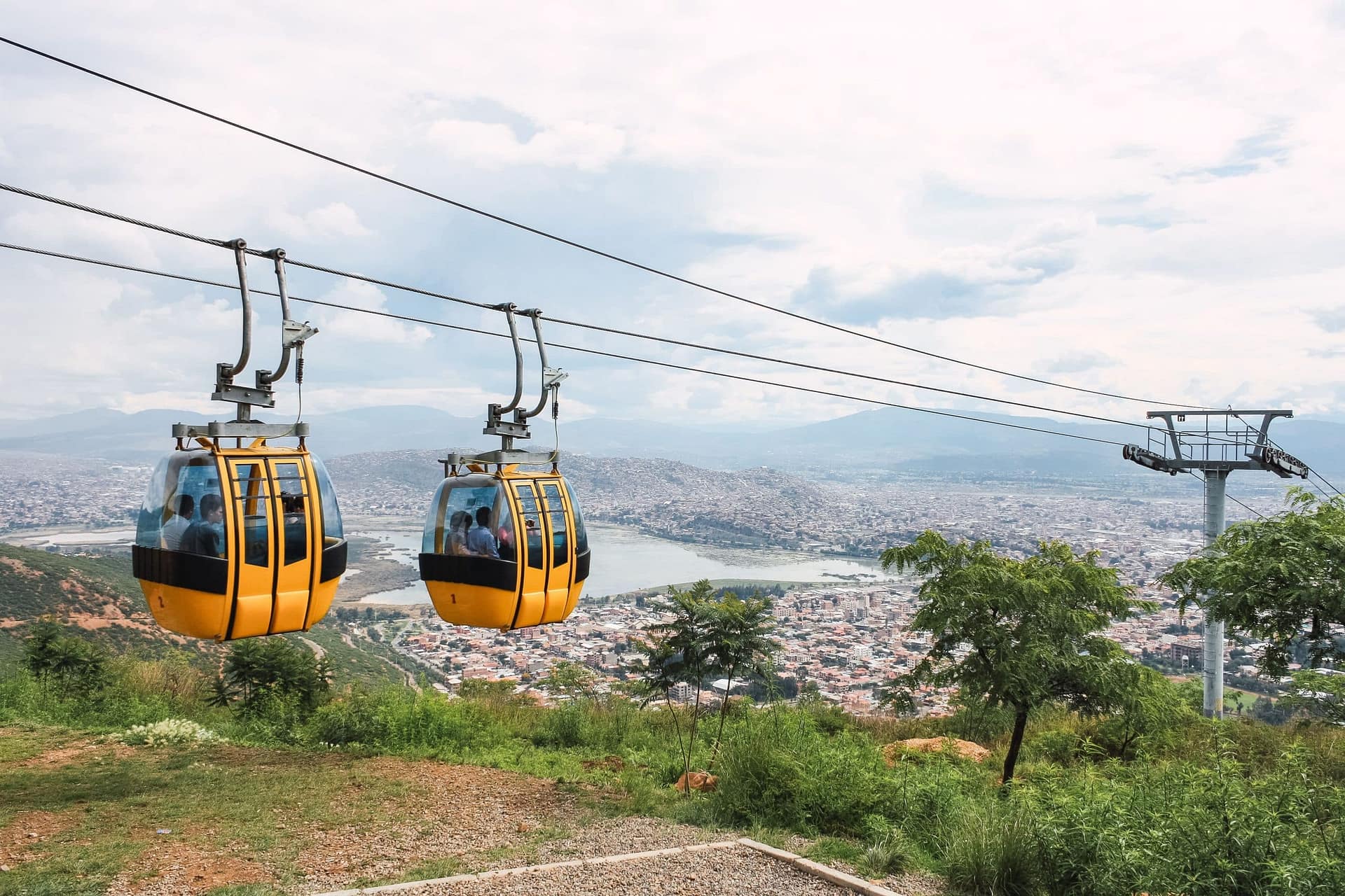 Yellow cable cars climbing a green hillside above Cochabamba, Bolivia