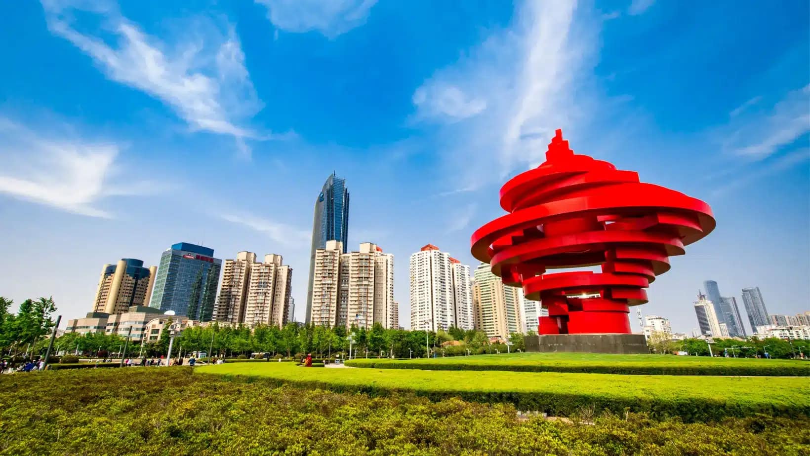 The red May Fourth sculpture in front of high-rise towers in Qingdao, China