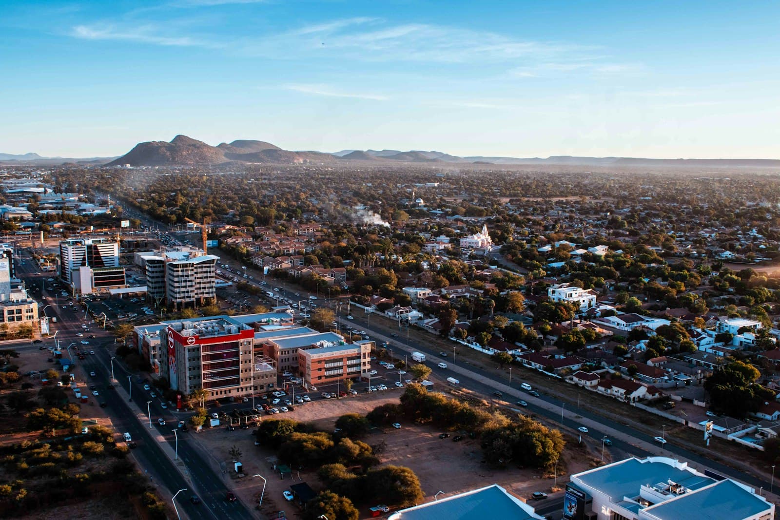 Aerial view of Gaborone at golden hour with low-rise offices, leafy neighborhoods and hills behind