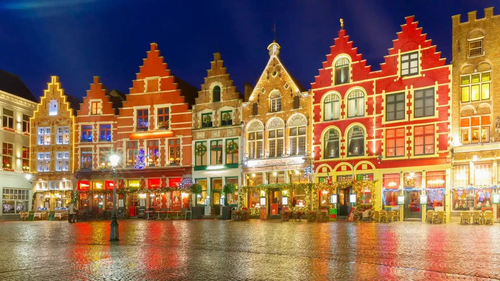 Colorful stepped-gable buildings lit up on the Markt square in Bruges on a winter evening