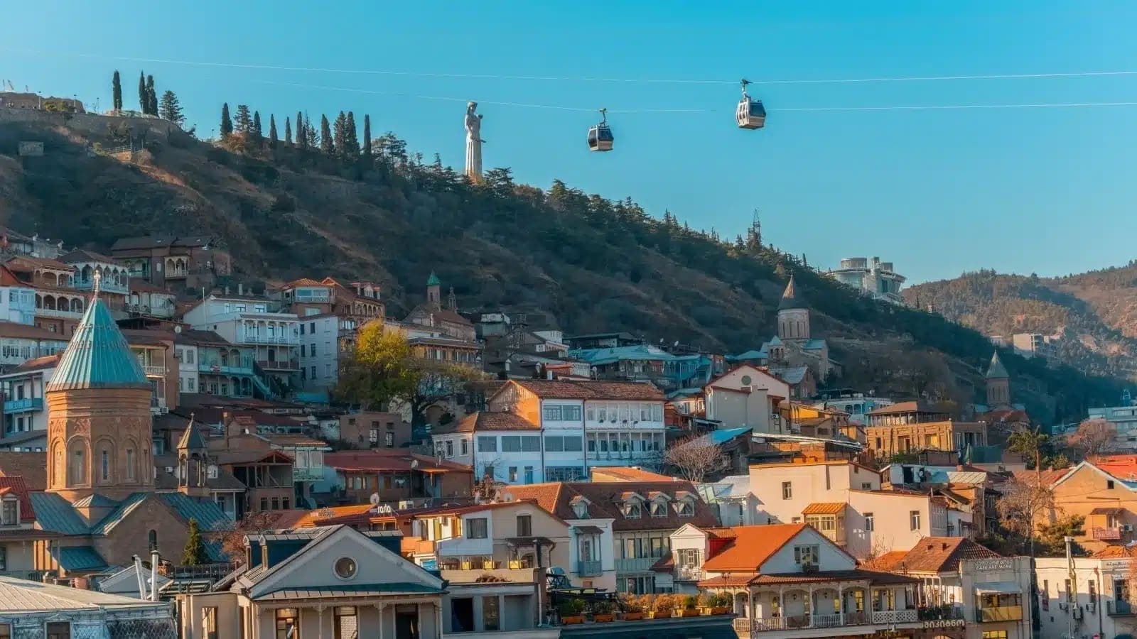 Tbilisi's old town on a sunny hillside with cable cars passing overhead