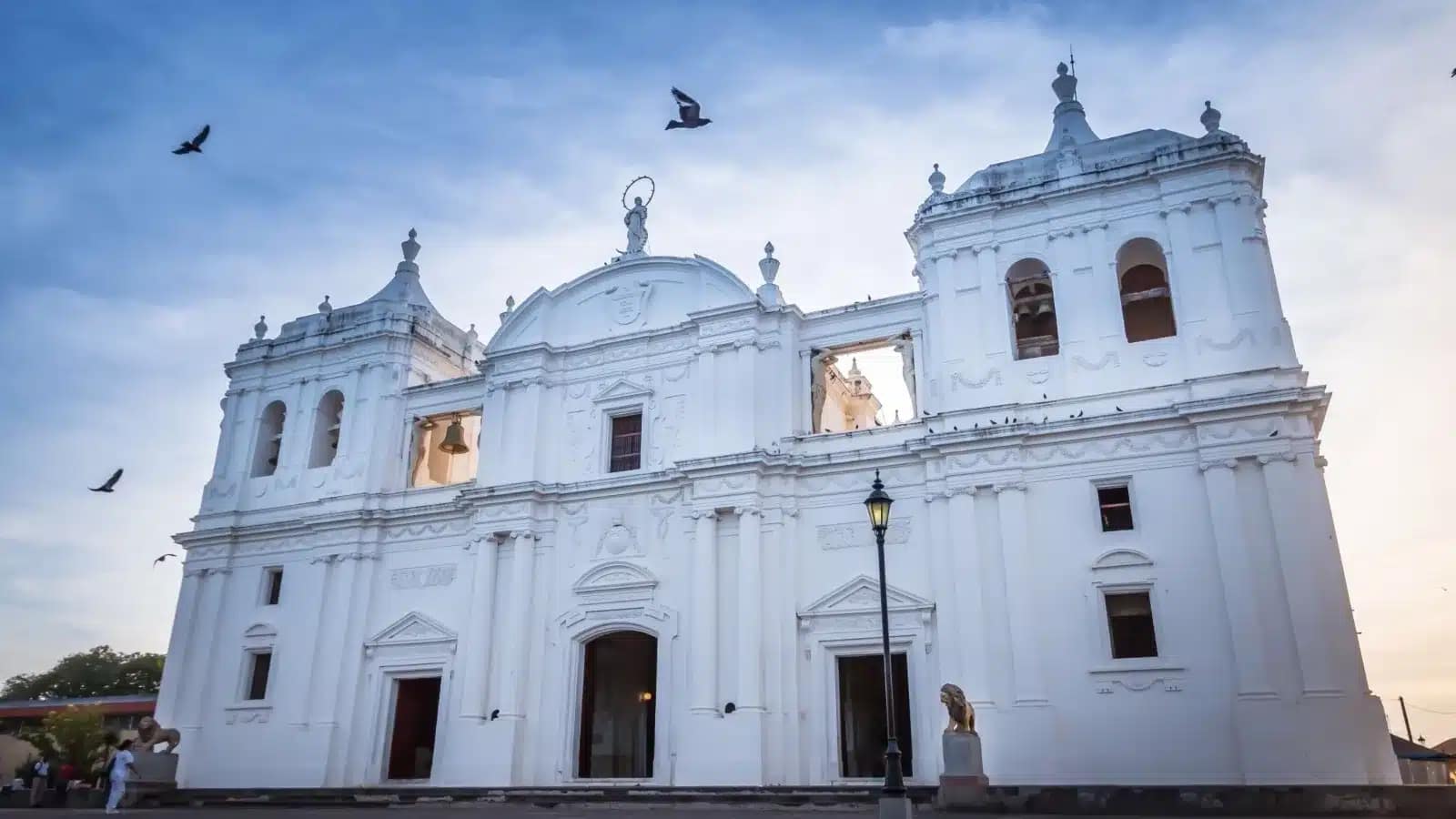 The white cathedral in León, Nicaragua, at dusk with birds overhead