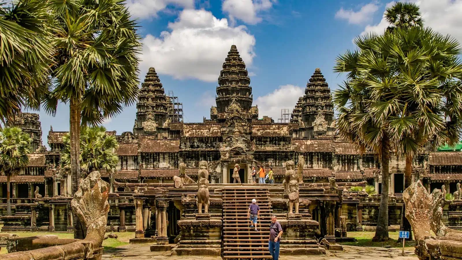 Angkor Wat's central towers framed by sugar palms under a blue sky
