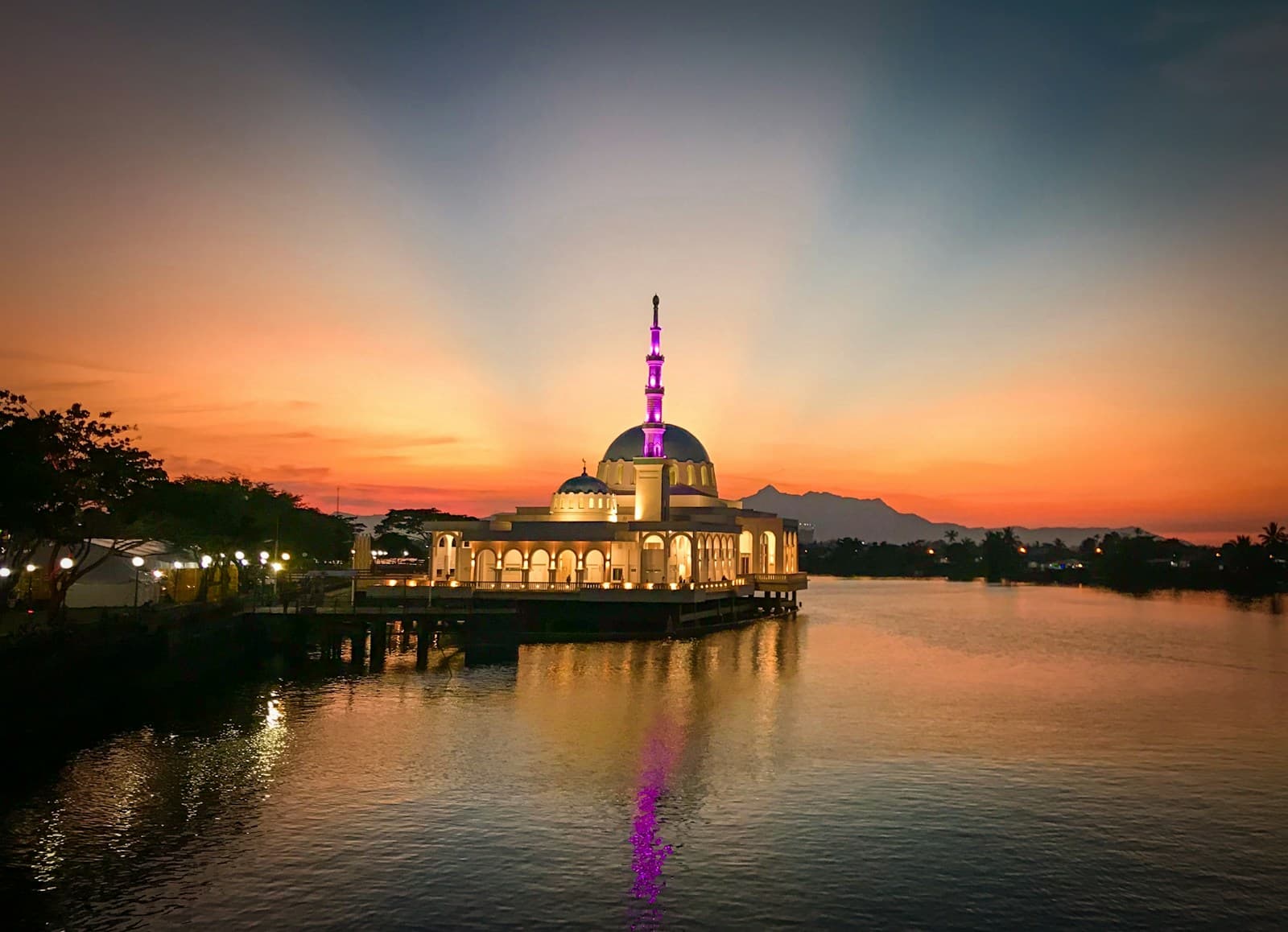 A lit mosque on the river in Kuching, Sarawak, at sunset