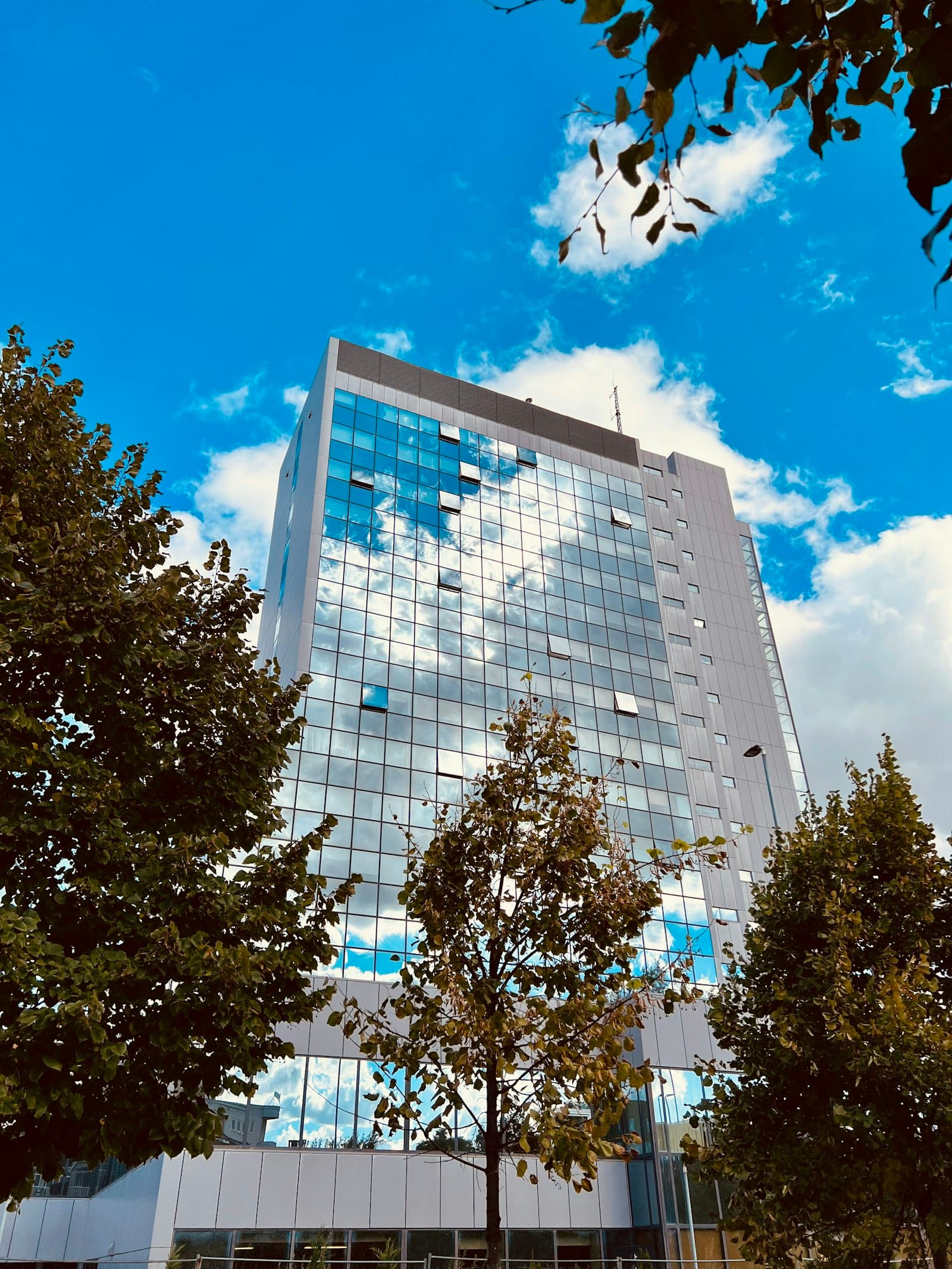 Glass-fronted high-rise against a blue sky in central Pristina