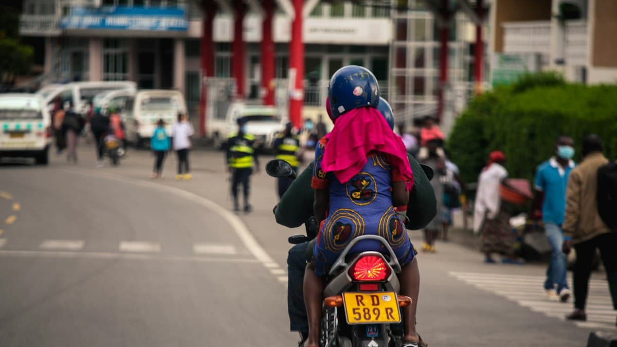 Two riders on a motorbike taxi on a street in Rwanda