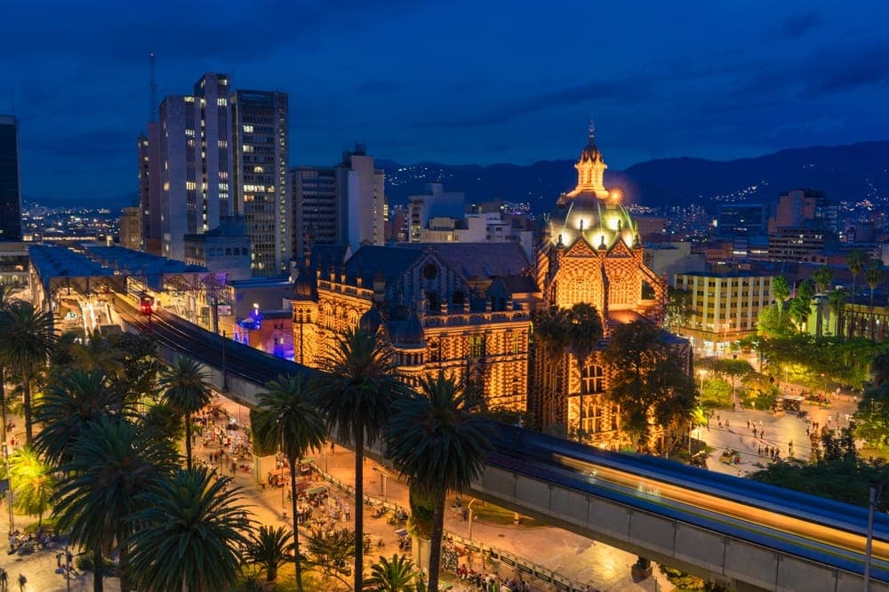 Medellín's elevated metro passing the Rafael Uribe Uribe palace at dusk