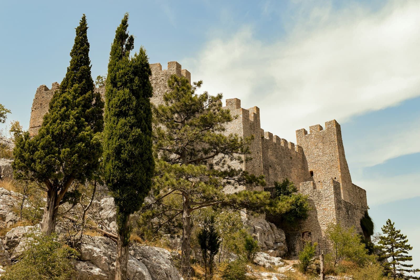 A medieval stone fortress among cypress and pine trees on a rocky hill in Bosnia and Herzegovina