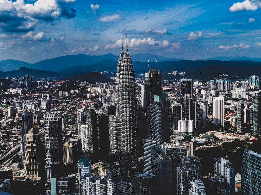 Kuala Lumpur's skyline and residential towers seen from above, with hills behind