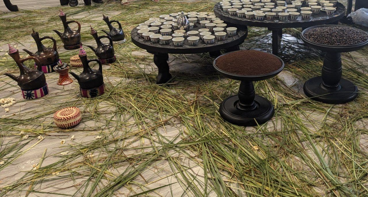 Clay jebena coffee pots, small cups and roasted beans set out for an Ethiopian coffee ceremony