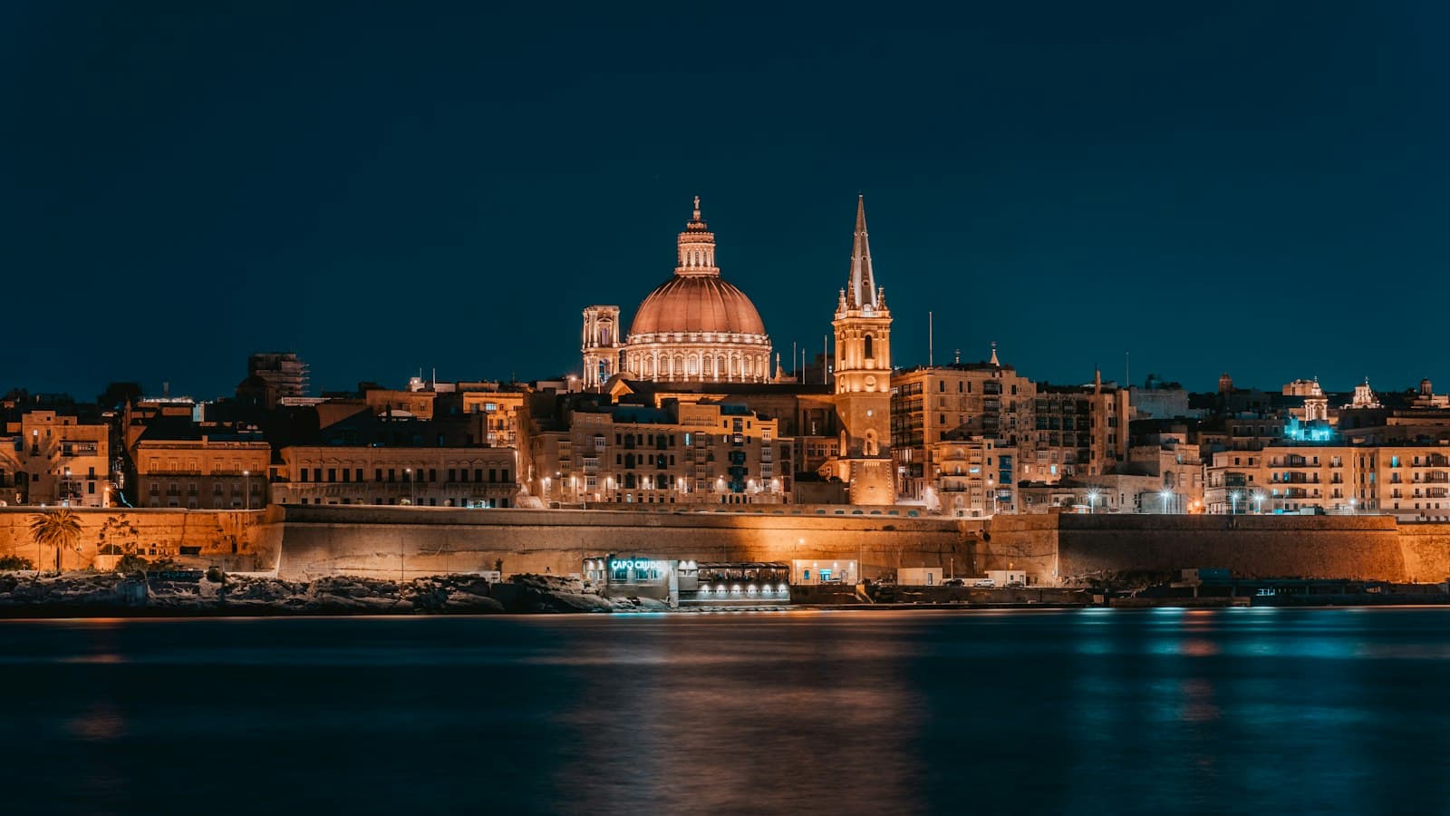 Valletta's skyline at night, with the dome of the Carmelite church lit up above the harbor walls