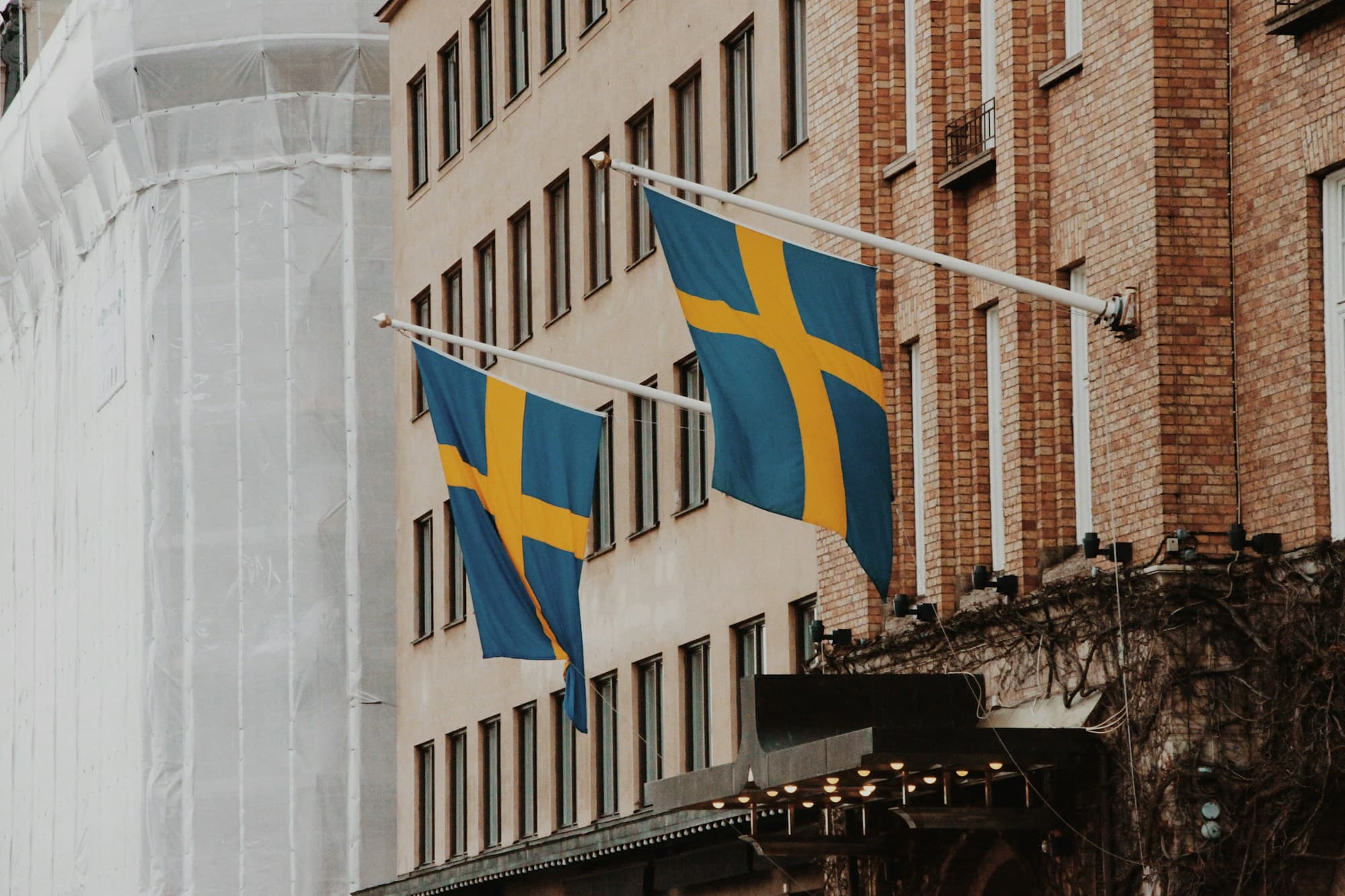 Two Swedish flags hanging from a building facade in Stockholm