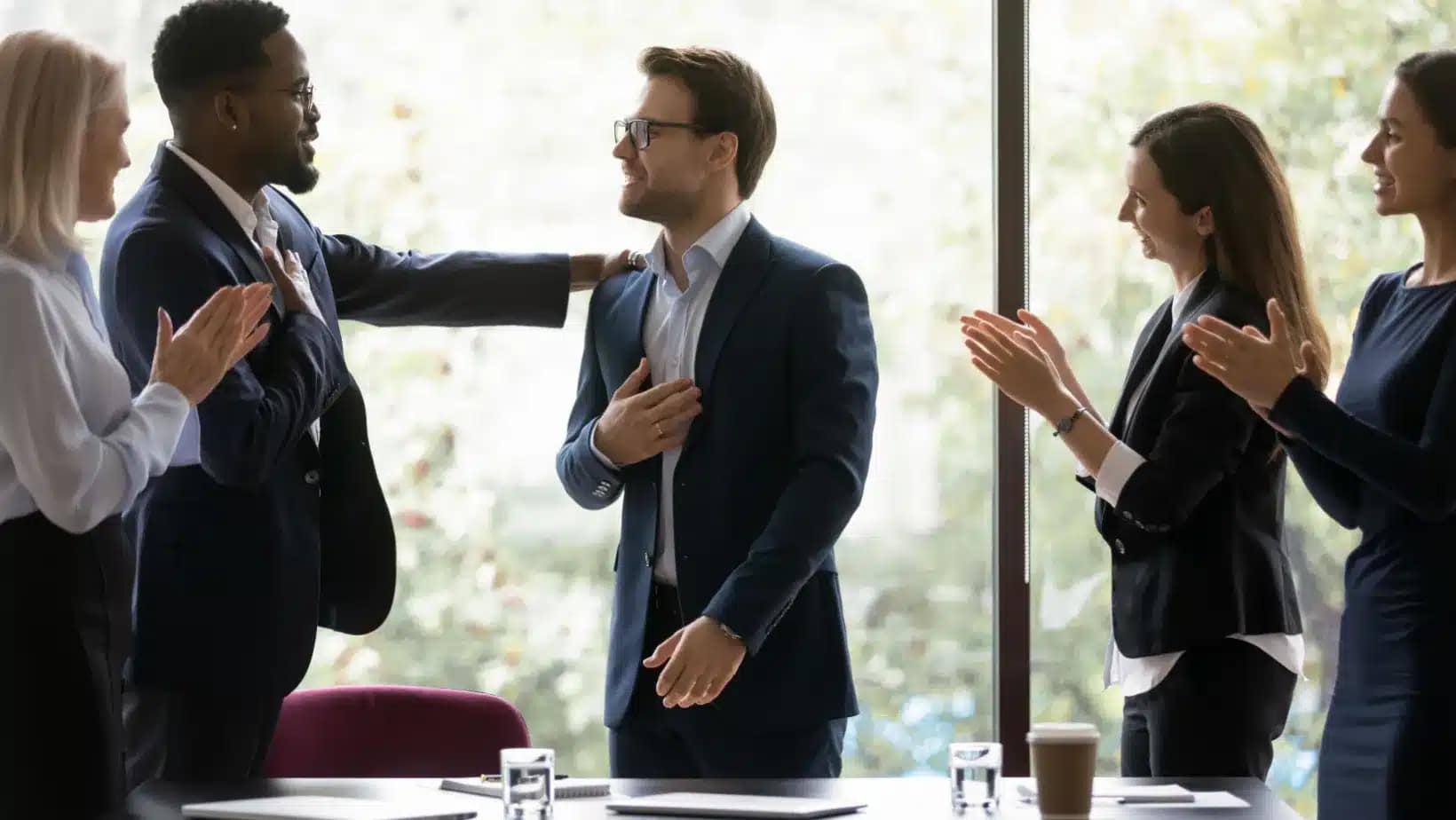 Colleagues congratulating a new hire in a meeting room