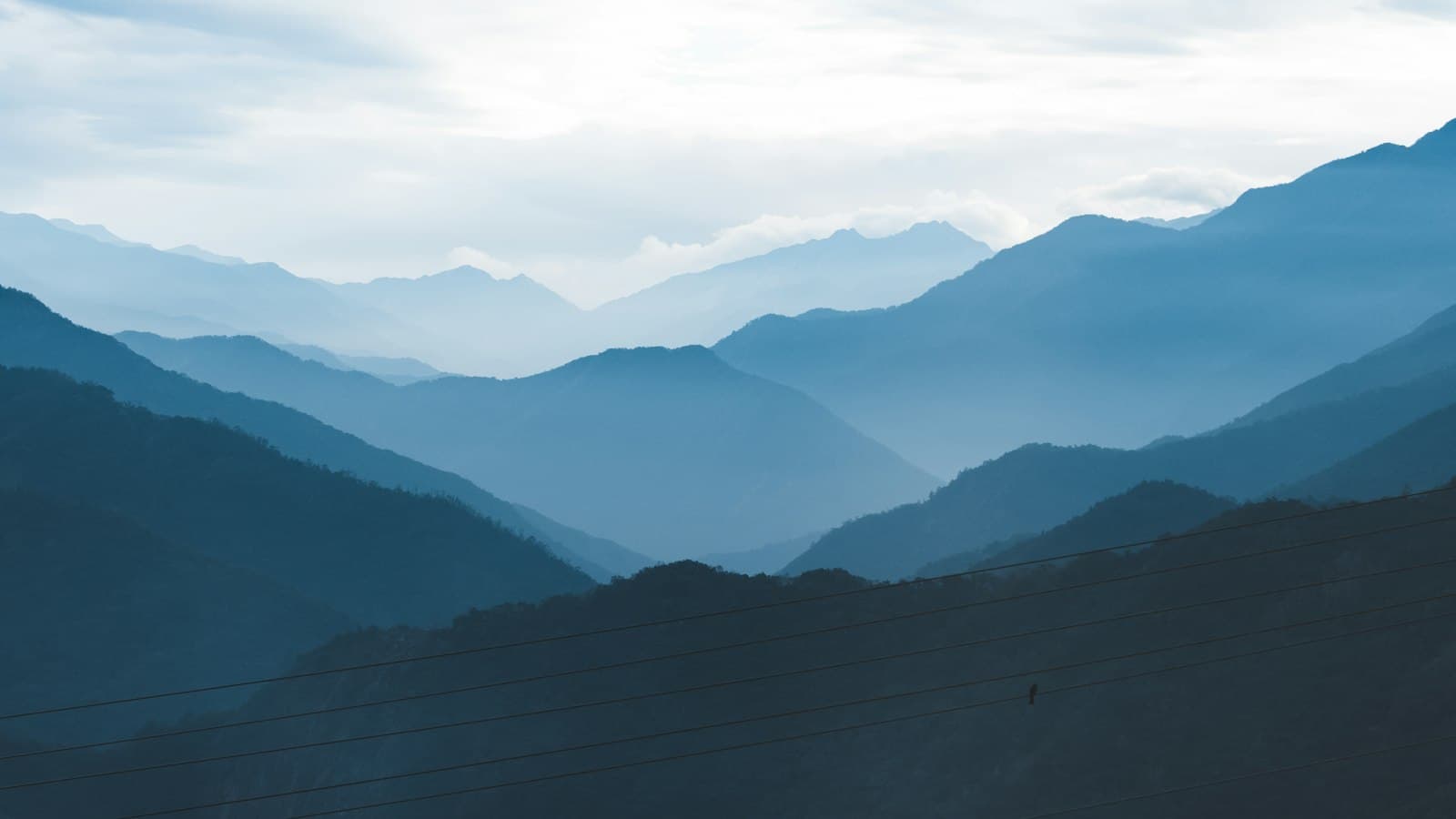Layers of blue mountain ridges in Taiwan's central range under a pale sky