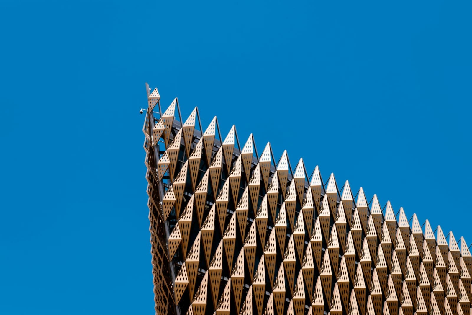 The gold, triangle-patterned facade of a Kuwait University building against a blue sky