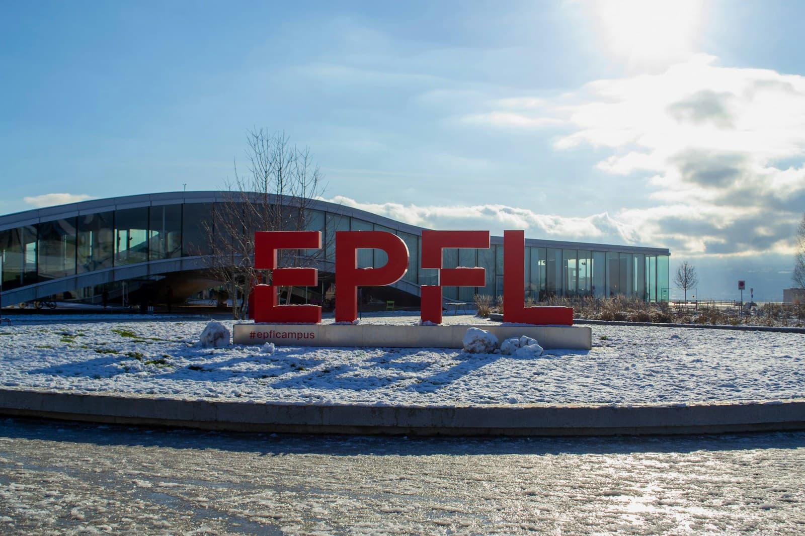 Red EPFL letters in front of the Rolex Learning Center on a snowy day in Lausanne