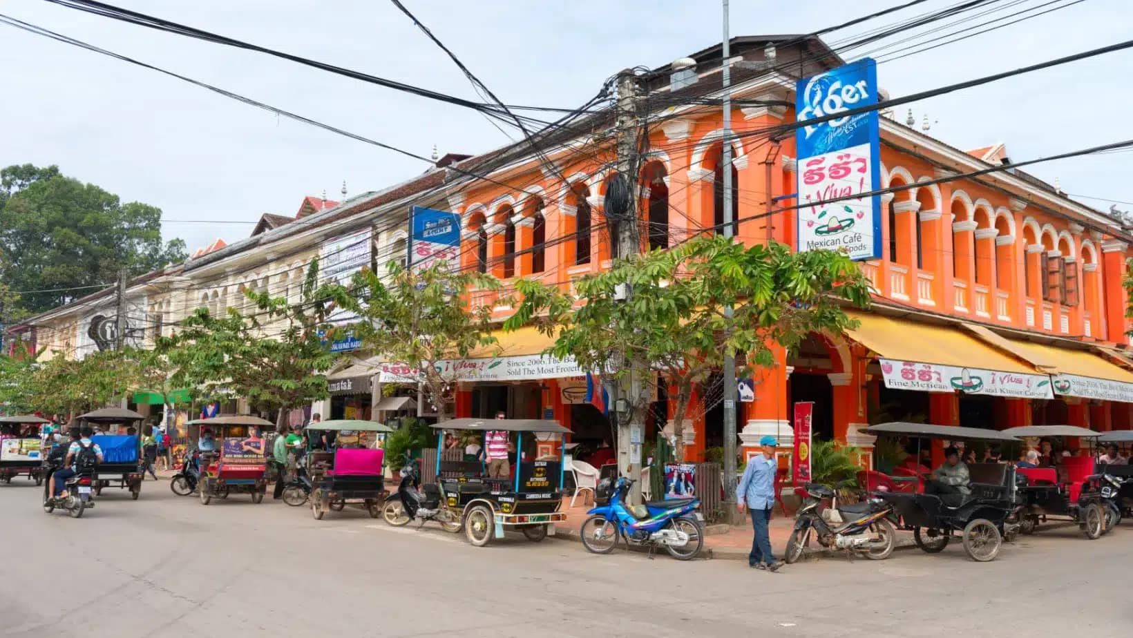 Tuk-tuks parked along a street of colonial shophouses in Siem Reap
