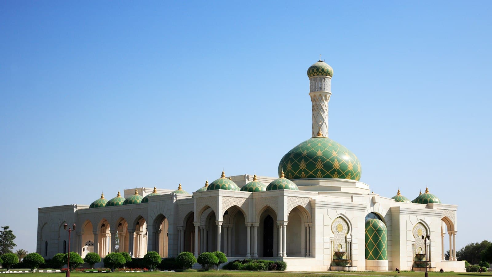 Zawawi Mosque in Muscat with green domes under a clear blue sky