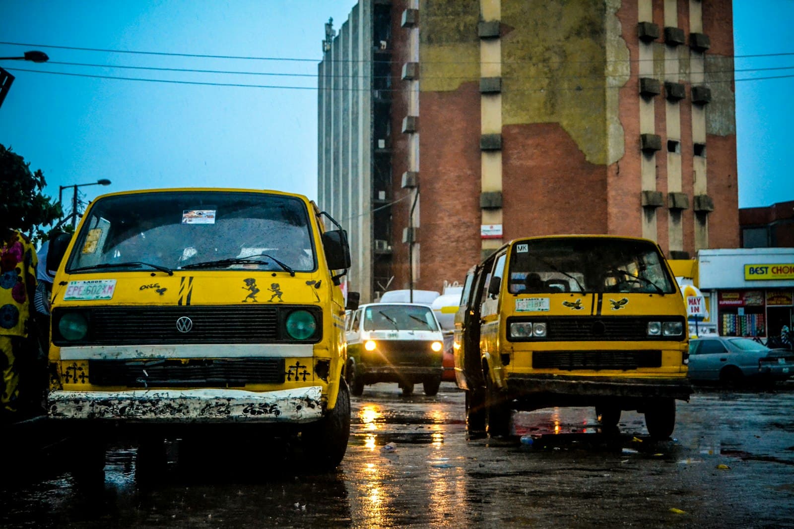 Yellow danfo minibuses on a wet street in Lagos at dusk