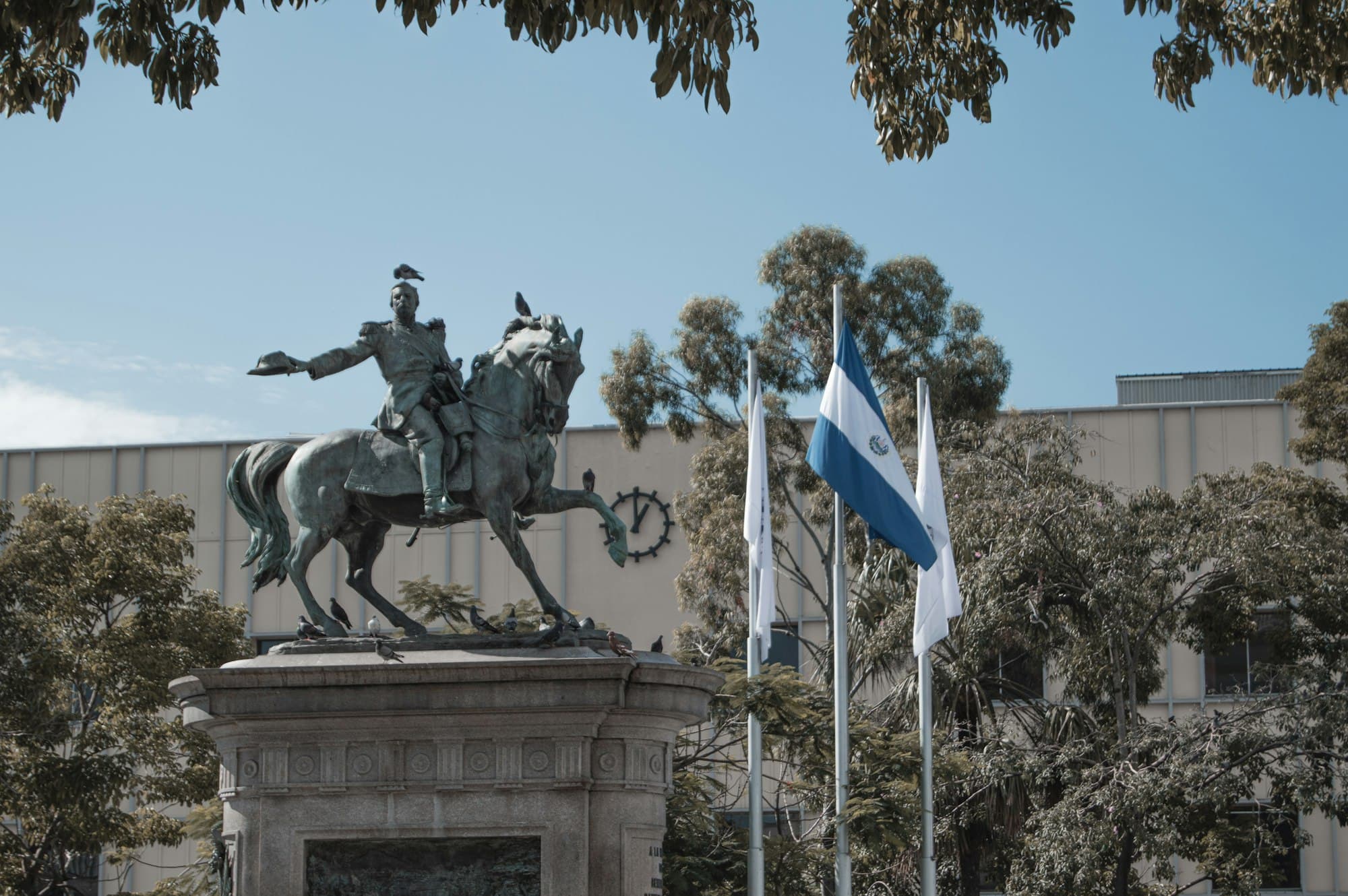 Equestrian statue and the Salvadoran flag in front of a government building in San Salvador