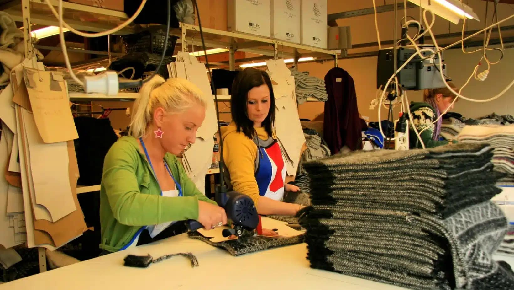Two women sewing wool fabric at a textile workshop in Iceland