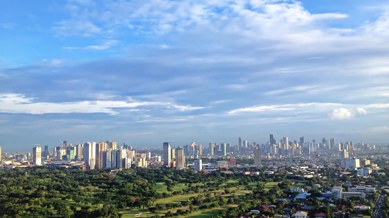 The Metro Manila skyline rising behind green fairways on a sunny day