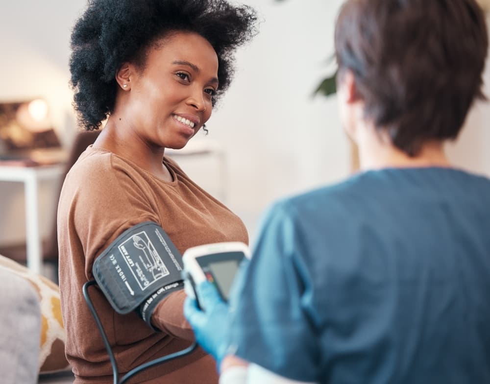 A nurse taking a smiling woman’s blood pressure