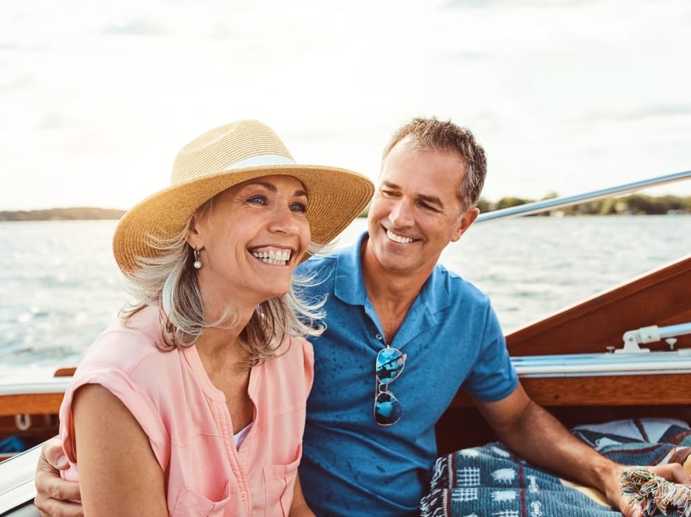A smiling couple on a boat on a sunny lake