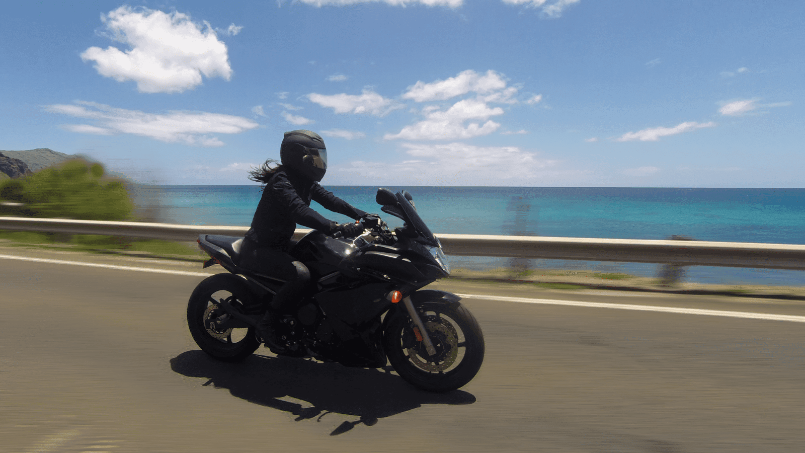 A motorcycle on a road in front of an ocean.