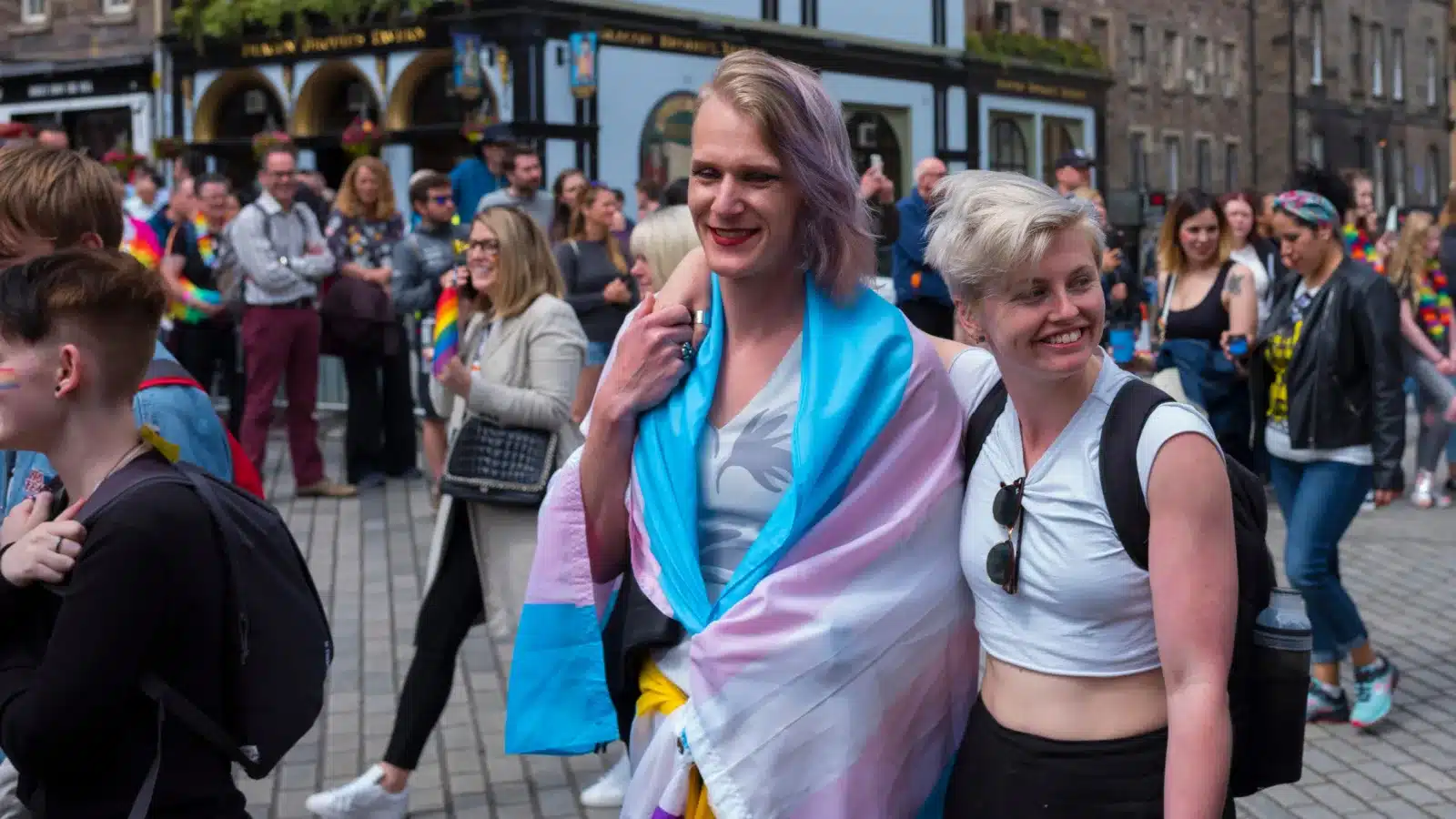A trans woman and her girlfriend walk in a Pride parade somewhere in Europe