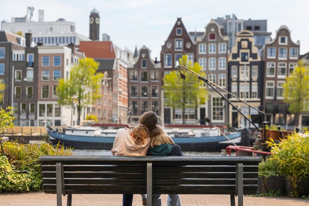 Two people on a bench looking across an Amsterdam canal