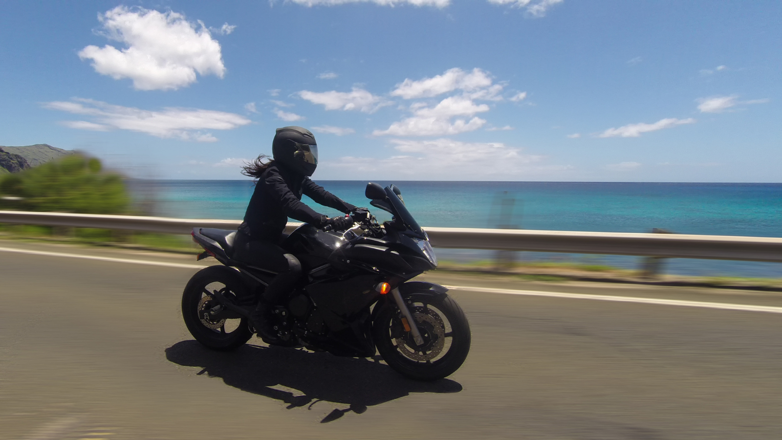 A motorcycle on a road in front of an ocean.